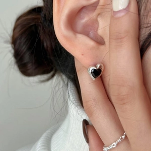 Minimalist 925 sterling silver heart stud earrings with black stones worn by a model