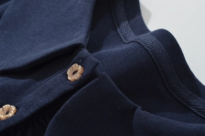 Gros plan sur le tissu en maille bleu marine avec boutons fleurs et détails du col