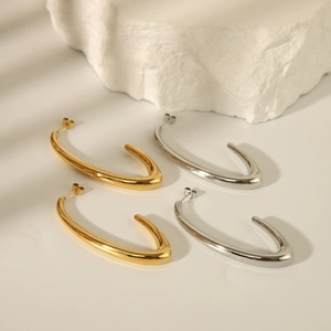 Modern hollow C-shape gold and silver stainless steel earrings on a white stone background