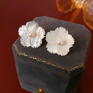 Gros plan de boucles d'oreilles fleur en perle et nacre sur un coffret en velours rétro