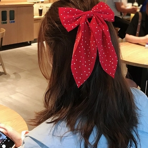Polka dot red bow hair clip with long ribbons shown on model in a Japanese style