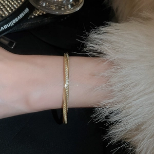 Macro view of gold-plated twisted bangle with micro-pave star and floral zircons