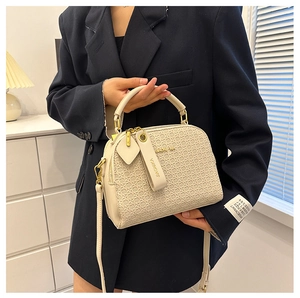 Detail of cream woven leather mini square bag with top handle and logo pendant charm