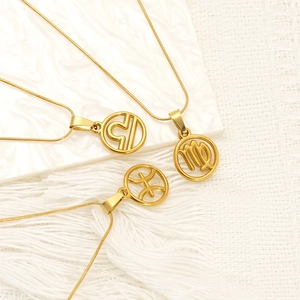 Gold hollow zodiac necklace set with Libra and Virgo pendants on white fabric