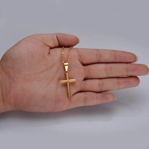 Detailed close-up of a gold stainless steel cross pendant necklace held in hand