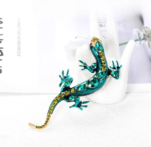 Détail macro d'une broche lézard avec cristaux vert émeraude et émail sarcelle