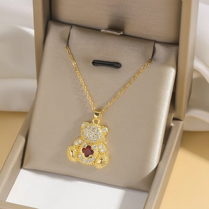 Golden bear necklace with white zircons and red clover stone in a jewelry box