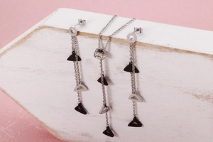 Detail of triangle tassel necklace and earrings set with rhinestones on white wood