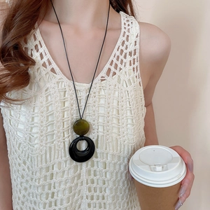 Detail einer geometrischen langen Kette mit grüner Perle und schwarzem Ring am Modell