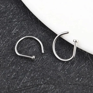 Detailed view of two silver D-shaped nose rings with smooth metallic finish on dual background