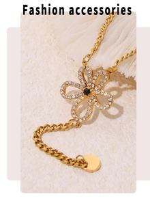 Close-up of a gold flower necklace with zircon petals, black gem core and Cuban chain