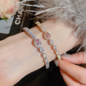 Detail of luxury gold and silver bracelets featuring pink oval zircon with halo setting