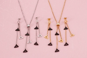 Detail of geometric triangle tassel necklace and earrings set in gold and silver finish