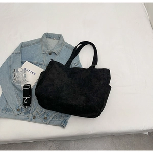 Detail of black corduroy tote bag showing soft ribbed texture and detachable shoulder strap