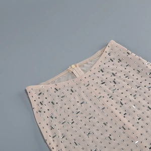 Close-up of beige mesh fabric with glittering rhinestones and hidden zipper detail