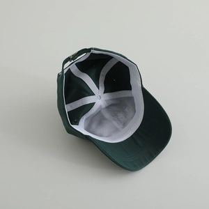 Detailed interior of dark green cotton baseball cap with white seams and metal buckle
