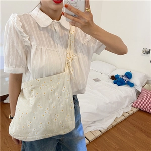 Detail of adjustable knotted strap and daisy floral print on cream canvas tote bag