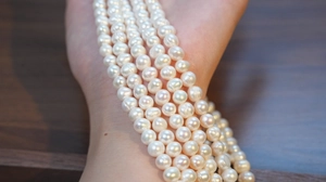 Detail of natural freshwater pearl necklace wrapped around wrist showing high luster and quality
