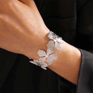 Detailed view of silver flower bracelet with textured petals on black fabric background