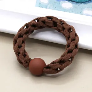 Detailed view of coffee brown braided hair tie with matte bead on elegant background