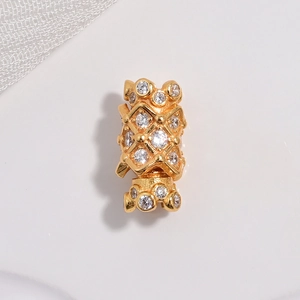 Macro detail of golden hollow cylinder bead with sparkling pavé cubic zirconia setting