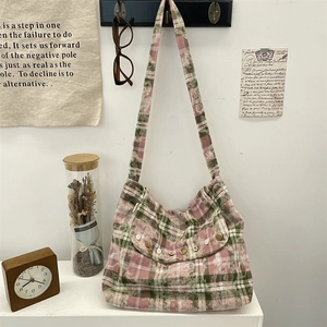 Détail du sac bandoulière en toile à carreaux rose et vert avec bouton décoratif en bois