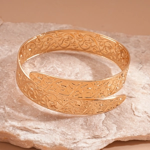 Detailed macro view of engraved gold geometric bypass cuff bracelet with arabesque patterns