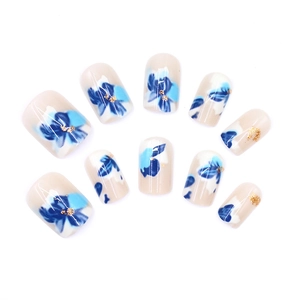 Faux ongles camélia bleu aquarelle avec touches dorées sur base de couleur nude