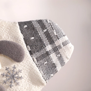 Off-white knit Christmas stocking with gray plaid cuff and felt snowflake decoration