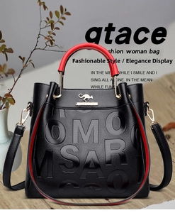 Detail of black pebbled leather tote with red handles and embossed OMO SARCO lettering