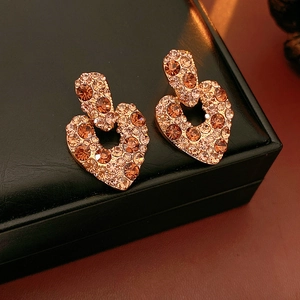 Gros plan de boucles d'oreilles cœur vintage dorées avec zircon champagne sur cuir noir
