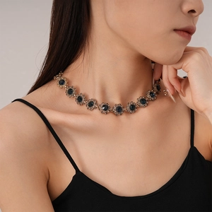 Detail of vintage gold flower necklace with dark blue crystals on model's neck