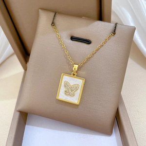 Close-up of golden shell butterfly necklace with crystals in premium gift packaging