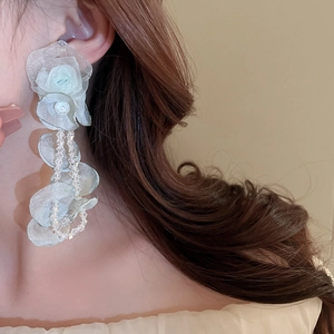 Détail de boucles d'oreilles en tulle bleu clair avec glands en cristal sur un mannequin