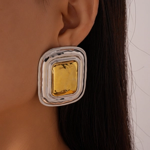 Close-up of model wearing large geometric two-tone hammered metal earrings in gold and silver