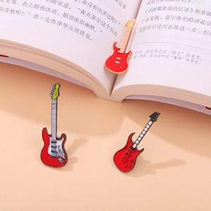 Detailed close-up of three enamel guitar brooches in red, gold, and black colors