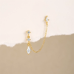 Detail of gold chain earring with sparkling zircon stones and marquise-cut pendants
