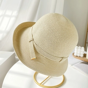 Elegante cappello di paglia beige con nastro decorativo su supporto minimalista
