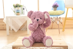 Detail of pink teddy bear plush with spiral fur texture and floral neck ribbon