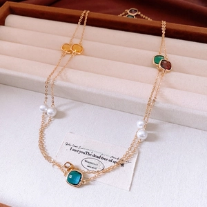Detail of vintage gold necklace featuring faceted colorful gemstones and white pearls