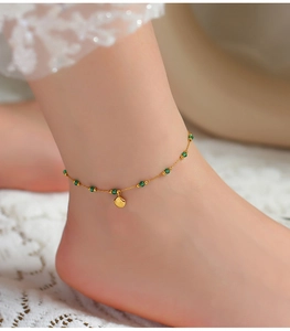 Detail showing vintage gold shell charm and green beads on anklet over lace