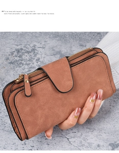 Brown frosted suede long wallet with double zippers and buckle closure held by hand