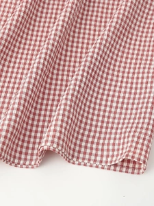 Close-up of red and white gingham fabric texture with fine stitching on the midi dress