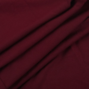Gros plan sur la texture du tricot bordeaux montrant le tissage fin et la matière douce