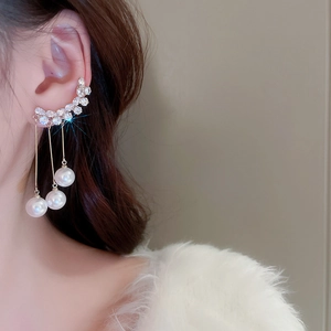 Close-up of elegant gold tassel earrings with pearls and crystals on a model