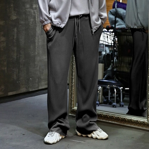 Close-up of dark grey wide leg trousers featuring vertical pleated texture and drawstring waist
