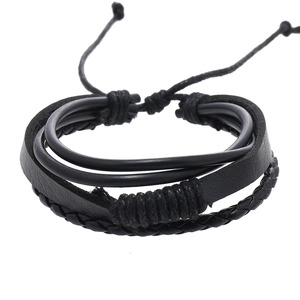 Detail of multi-layer black leather bracelet featuring braided ropes and adjustable knots
