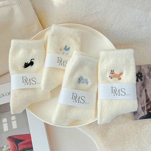 Detailed embroidery of animals on soft off-white thermal socks displayed on a round tray