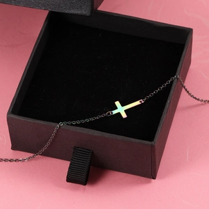 Macro detail of rainbow iridescent cross pendant on black chain in a premium jewelry box