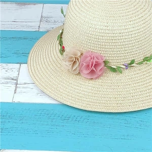 Close-up of handmade straw hat featuring decorative pink floral fabric and green vines